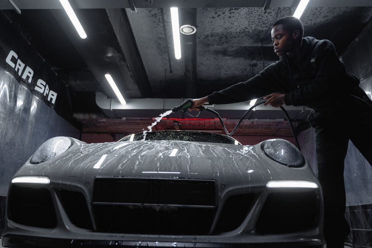 An enthusiast detailing a dark car in clean, controlled light